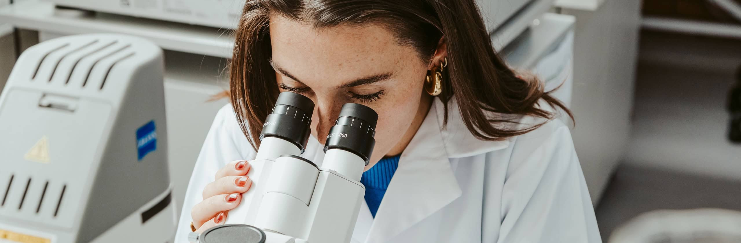 Hana Faulds looking through a microscope in lab environment